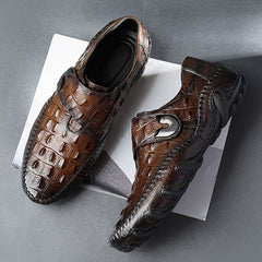 A pair of brown crocodile-embossed leather loafers featuring a hook and loop fastener and rubber soles.