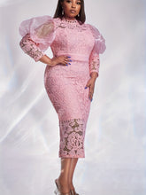 A woman wears a pink lace midi dress with puff sleeves and a round neckline.