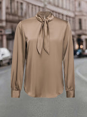 A champagne-colored satin long-sleeve shirt featuring a high neck with a lace-up tie detail.