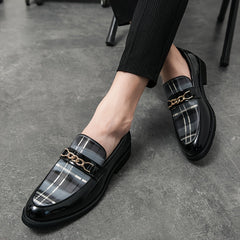 Men's black plaid slip-on loafers featuring a gold-tone chain detail and a pointed toe.