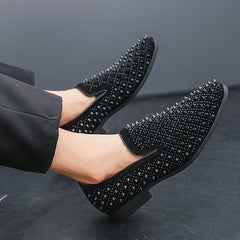 A pair of black slip-on loafers covered in small spikes with a round toe and rubber sole.