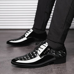 A pair of black and white pointed-toe dress shoes with a patterned finish and lace-up closure.