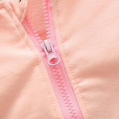 Close-up of a light pink baby jacket featuring a matching plastic zipper.