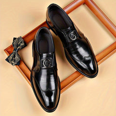 A pair of black pointed-toe loafers with a silver G-logo buckle, displayed with a patterned bow tie.