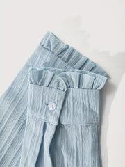 A close-up of the light blue ruffled cuffs on a long-sleeved, textured button-up blouse.