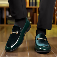 A pair of dark green velvet and patent leather loafers with gold-tone metal hardware.