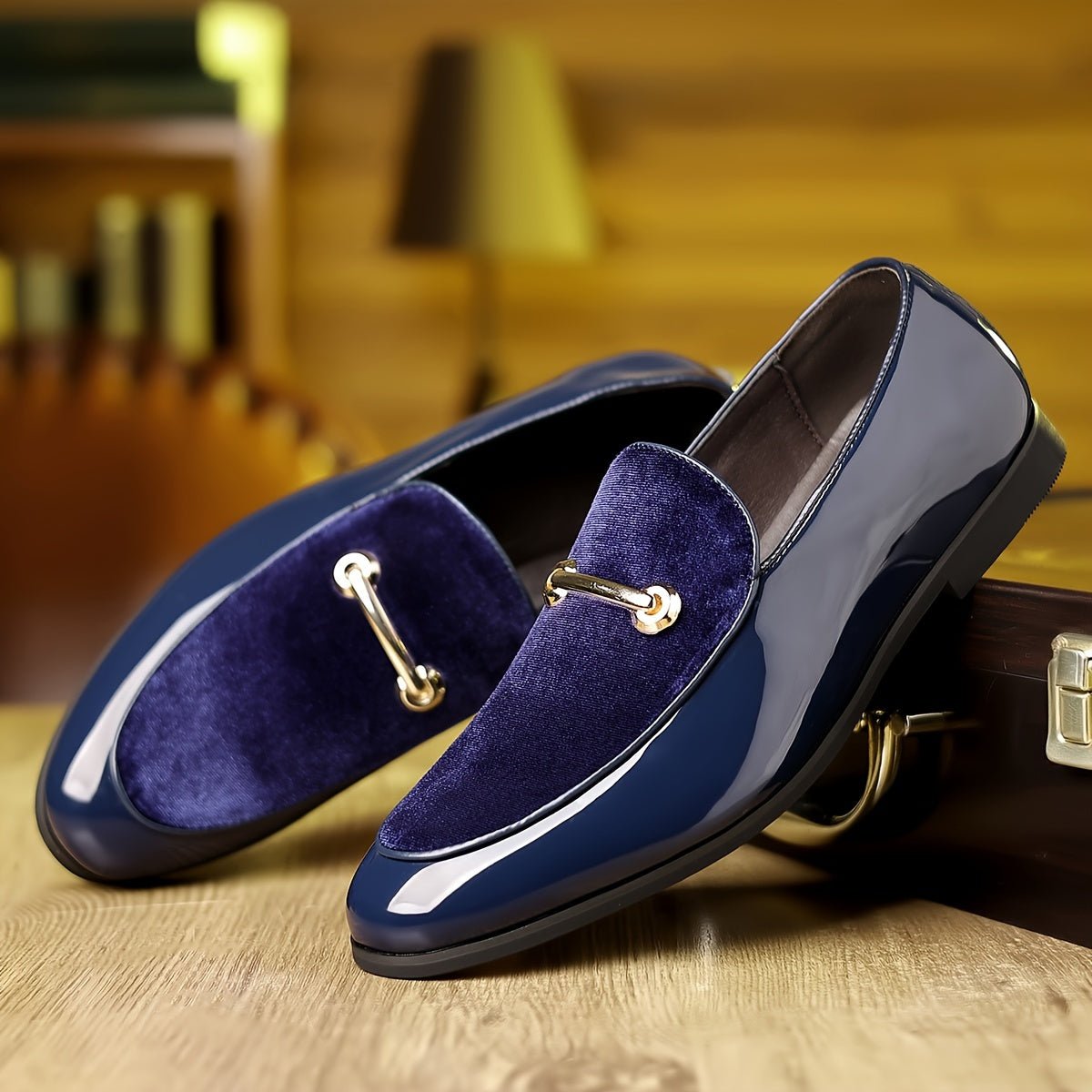 A pair of navy blue slip-on loafers featuring a velvet panel and a gold-tone metal bit detail.