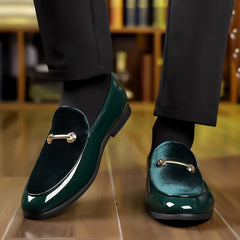 A pair of dark green velvet and patent leather loafers with gold-tone metal hardware.
