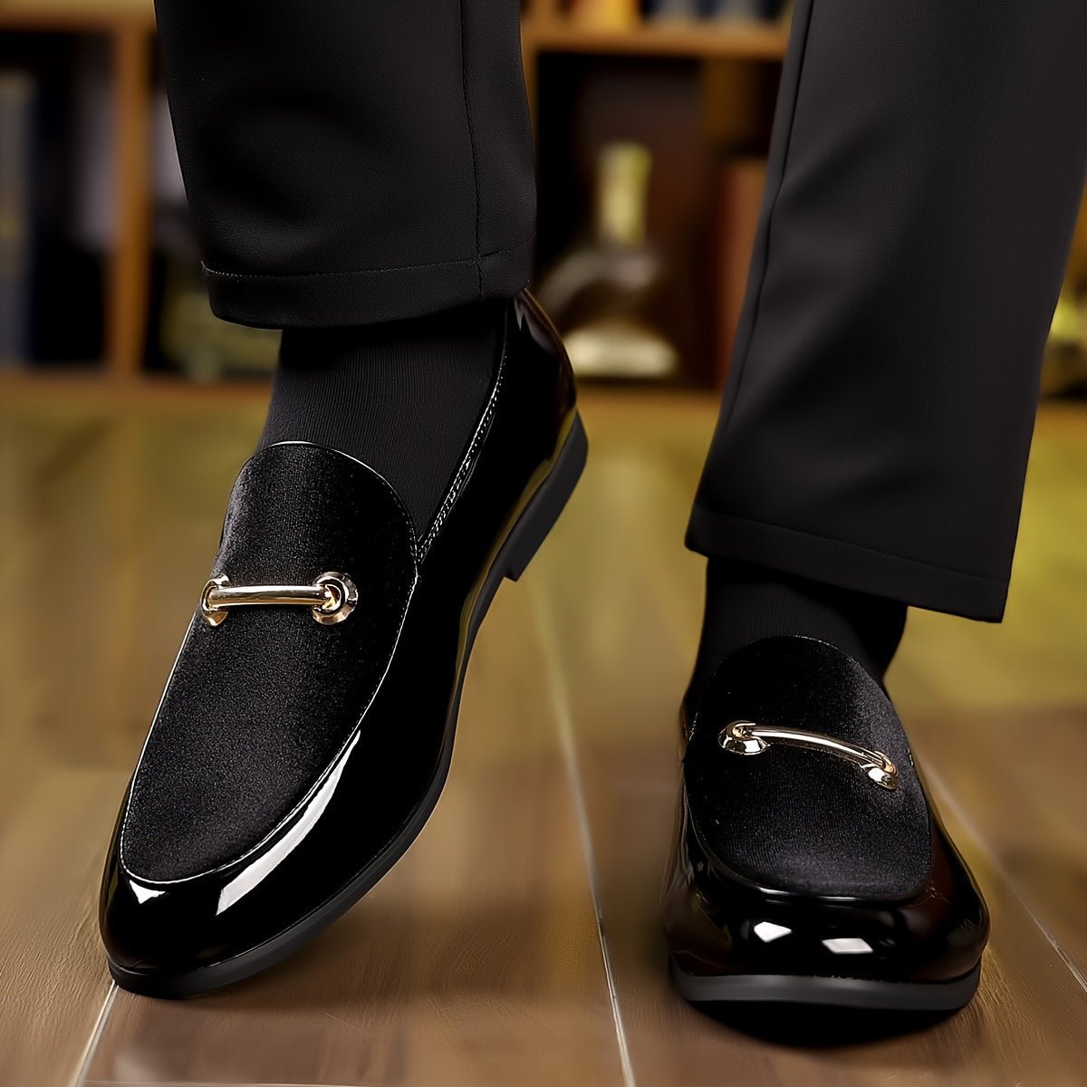 A pair of black slip-on loafers featuring a velvet-textured vamp and a gold-tone metal bar detail.