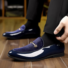 A pair of navy blue slip-on loafers featuring a velvet-textured vamp and a gold-tone metal bit.
