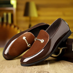 A pair of brown slip-on loafers featuring a glossy finish, suede-textured vamp, and gold-tone hardware.