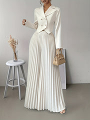 A woman wears a white double-breasted cropped blazer and matching high-waisted pleated pants.