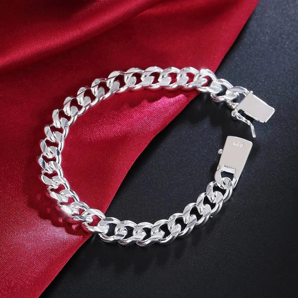 A 925 Sterling Silver Solid 10mm chain bracelet for men and women with a clasp rests on a black surface, partially draped over red satin, perfect as noble wedding jewelry, fashion charm, or party birthday gift.