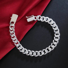 The 925 Sterling Silver Solid 10mm Chain Bracelet for men and women is shown on a dark surface beside red fabric, highlighting its secure clasp and elegant design—ideal jewelry for weddings, parties, or birthday gifts.