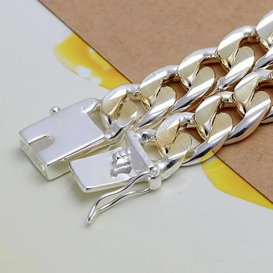 Close-up of the 925 Sterling Silver Solid 10mm Chain Bracelet for men and women, featuring silver and gold tones with a box clasp, displayed on a yellow and brown background—perfect as noble wedding jewelry or a fashionable birthday gift.