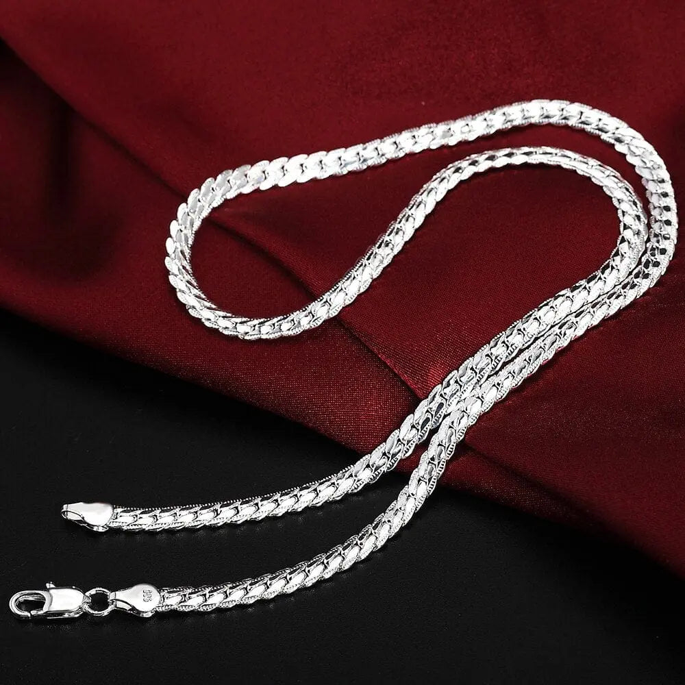 A 925 silver color European style retro 6MM flat chain necklace and bracelet set (S085), perfect for Christmas gifts for men and women, is displayed on a smooth surface with red satin cloth and a black background.