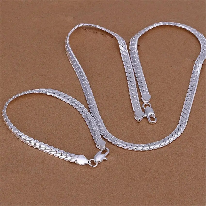 Two 6MM flat 925 silver color chain necklace and bracelet jewelry sets (S085) in European retro style are arranged on a brown surface—fashionable Christmas gifts for men and women.