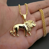 A gold-plated stainless steel lion pendant necklace held in a hand.