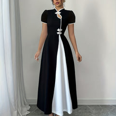 A woman wears a black and white midi dress with a mandarin collar and decorative buttons.
