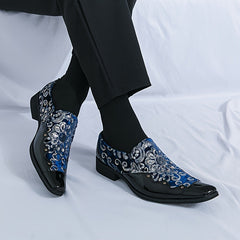 A pair of men's black and blue floral patterned slip-on shoes with a glossy toe cap.