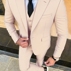 A man wears a light beige three-piece suit with a white shirt and black tie.