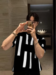 A man wears a black short-sleeve knitted sweater featuring a white vertical stripe pattern.