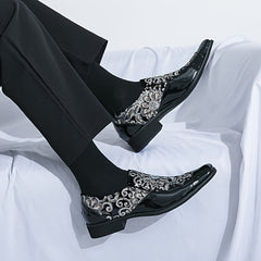 A pair of black slip-on dress shoes featuring a decorative floral sequin pattern on the sides.