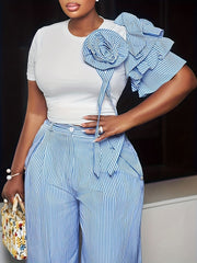 A woman wears a white crew neck top with a striped ruffled shoulder detail and matching pants.
