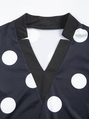 A close-up of a black V-neck dress featuring a white polka dot pattern and a solid black collar.