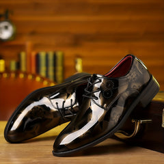 A pair of glossy black lace-up oxford dress shoes with a subtle floral pattern.