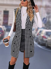 A woman wears a sleeveless, lapel-collared long vest featuring a black and white houndstooth pattern.