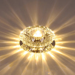 A modern circular crystal ceiling light emits a bright, starburst pattern of warm light.