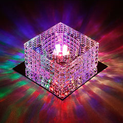 A square crystal ceiling light fixture casting colorful light patterns on a dark surface.
