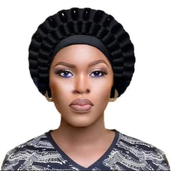 A woman wears a black, pleated, ready-made African auto gele headtie with a circular design.