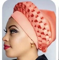 A peach-colored, ready-made African turban cap featuring a decorative, hollow-out braided trim.