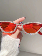 Cat eye sunglasses with red lenses and a rhinestone-encrusted frame held by a hand.