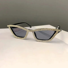 Cat eye sunglasses with a black frame encrusted with sparkling rhinestones and dark grey lenses.