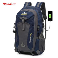 A blue and gray Anti-theft Mountaineering Waterproof Backpack for men is shown with "alaska 40L" text, a USB charging port linked to a smartphone, and "Standard" in red at the top left. Multiple compartments are visible.