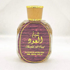 A bottle of Sheikh Al Oud perfume with a gold cap and a pink and black patterned label.