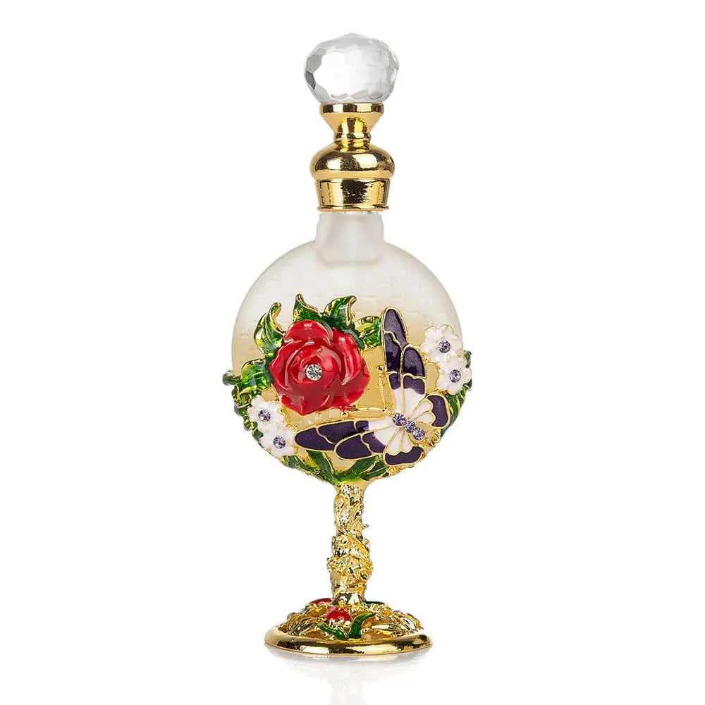 The Arabian Rich Middle Eastern style essential oil perfume "Reverses Paris, True Blue" features a decorative glass bottle with a gold base, red rose, purple butterfly, white flowers, and a round shape with a clear faceted stopper.