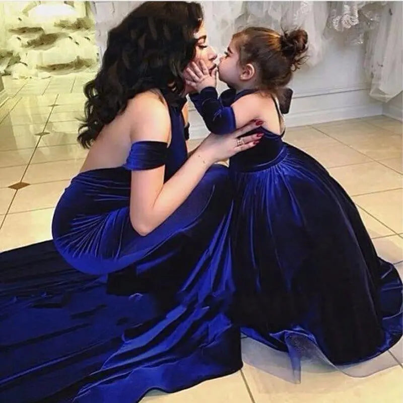 A woman and young girl in matching Backless Velvet Flower Girls Dress 2020 Off The Shoulder Mother Daughter royal blue gowns sit floor-to-floor, touching noses sweetly in timeless flower girl style.