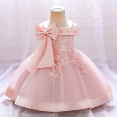 A light pink Bow Summer Dress for infant baby girls, featuring lace flower embroidery, a large shoulder bow, and a flared tulle skirt—ideal as a birthday party or wedding gown. Displayed on a child mannequin against a soft white background.
