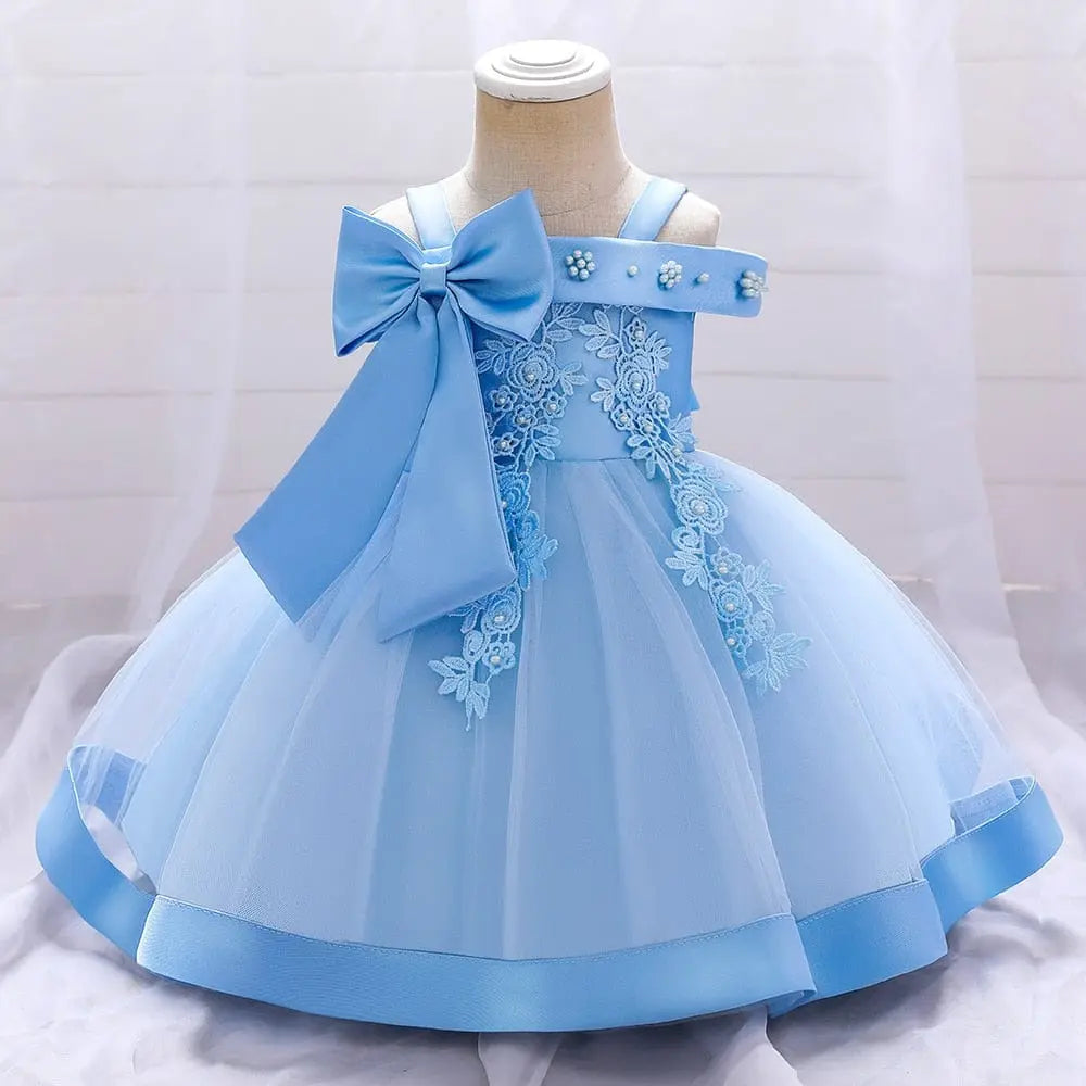 The Bow Summer Dresses Infant Baby Girl Birthday Party Dress features light blue lace floral details, a large chest bow, and pearl embellishments, shown sleeveless on a dress form against a soft white background.