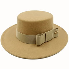 A tan flat-top fedora hat featuring a matching ribbon band with a bow and a small gold bee pin.