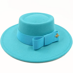 A bright turquoise flat-top fedora hat featuring a matching ribbon bow and a small gold bee pin.