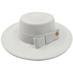 A white flat-top fedora hat featuring a matching ribbon bow and a small gold bee emblem.