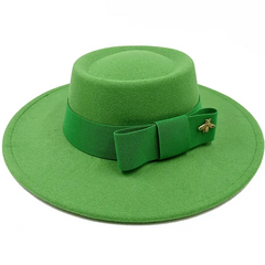 A bright green flat-top fedora hat featuring a matching ribbon bow and a small gold bee emblem.