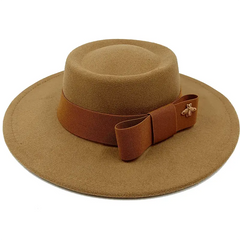 A tan felt fedora hat with a flat top, a brown ribbon bow, and a small gold bee emblem.