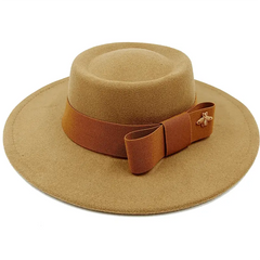 A tan felt fedora hat with a flat top, wide brim, and a brown bow band featuring a gold bee pin.
