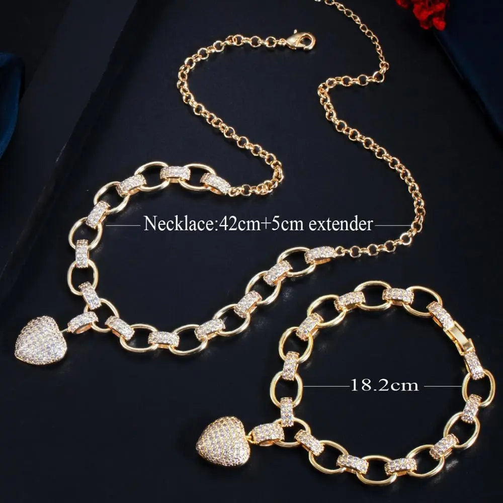 The CWWZircons 585 Gold Color Dangle Love Heart Charm Set (T468) features a cubic zirconia pendant necklace (42cm+5cm) and bracelet (18.2cm), both with large chain links, shown on a black background.